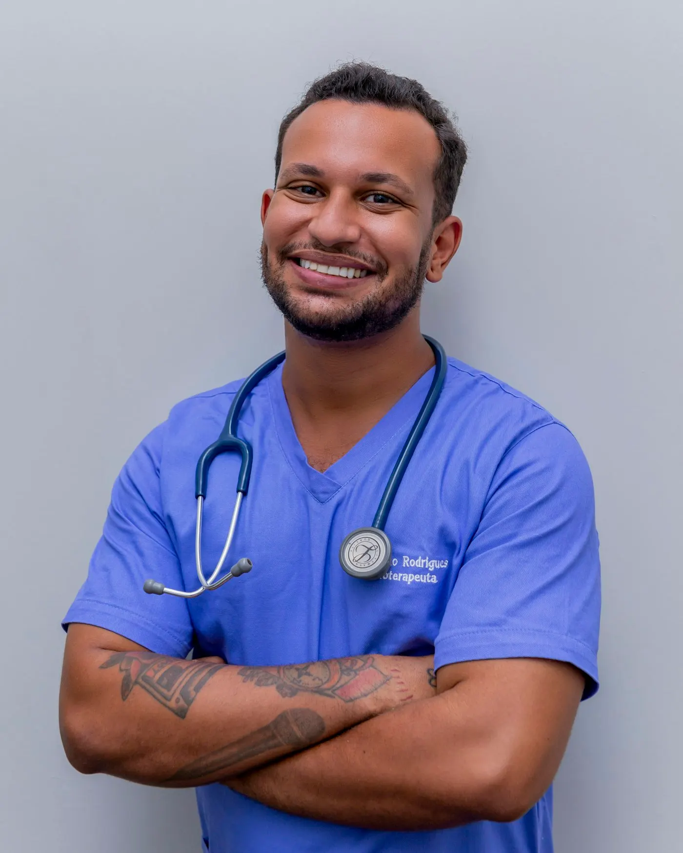 A smiling nurse in blue scrubs with a stethoscope