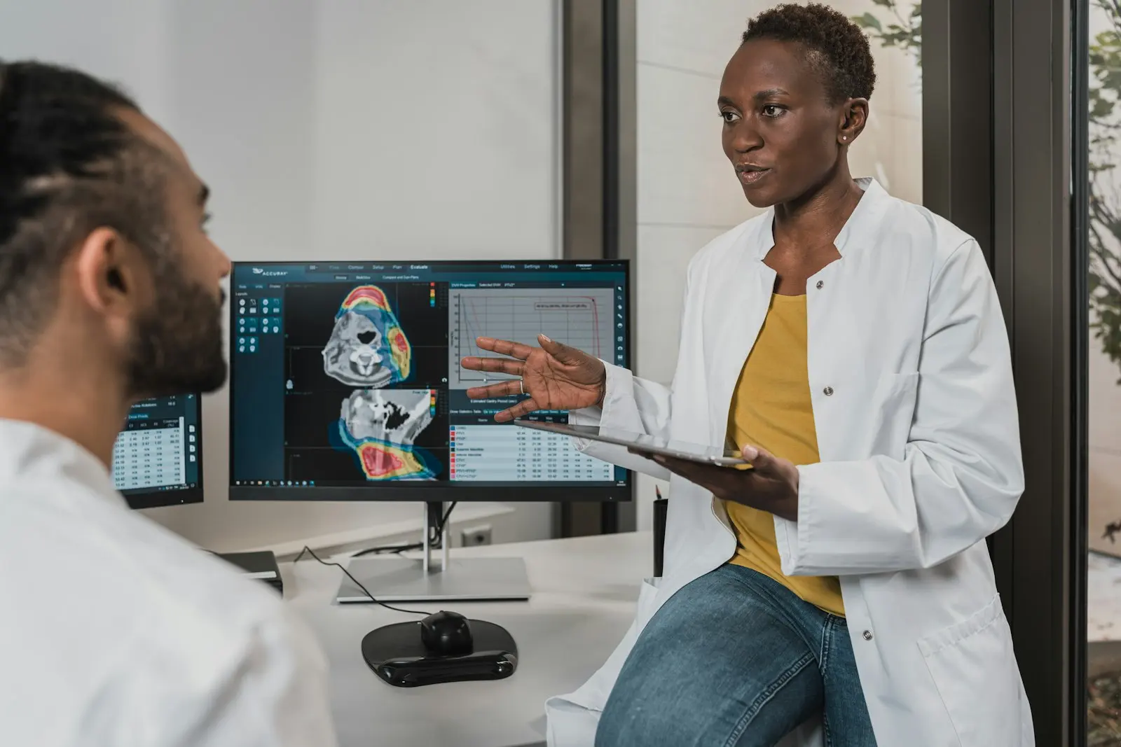 A radiologist discussing a scan with a colleague at a workstation