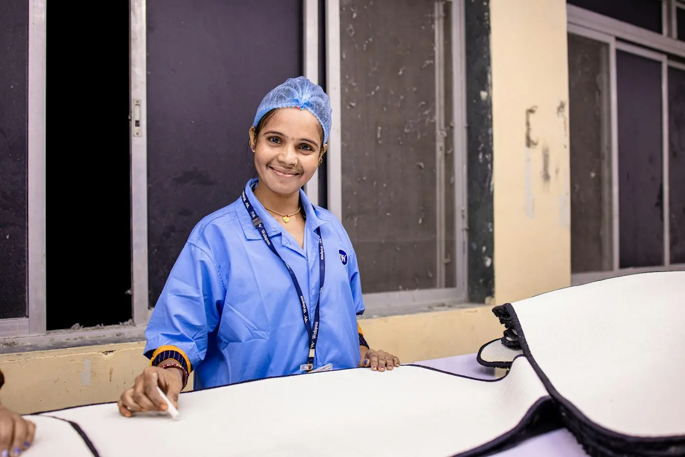 A smiling clinician in surgical attire in a ward