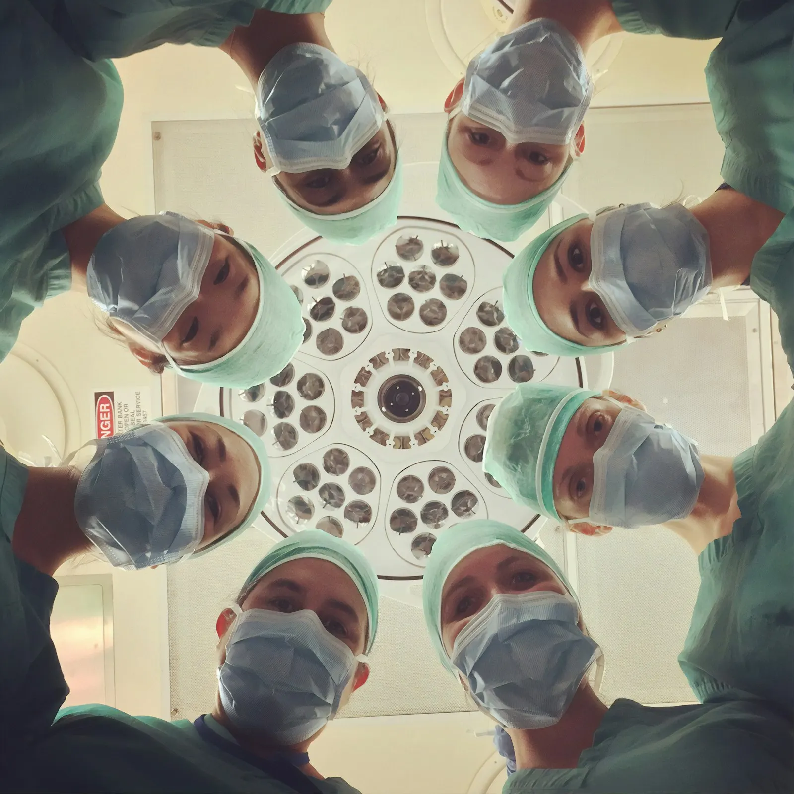 A surgical team in scrubs working together under theatre lights